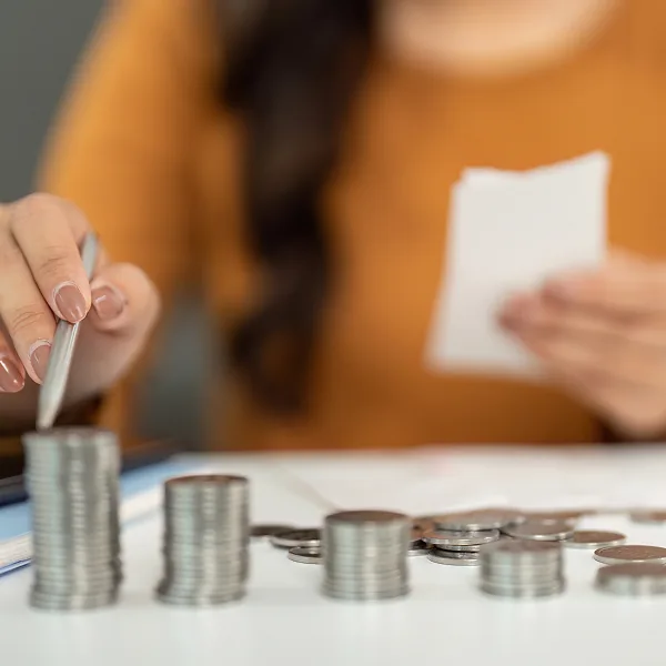 Femme comptant des pièces de monnaie avec un reçu en main pour couvrir des soins médicaux grâce à un prêt